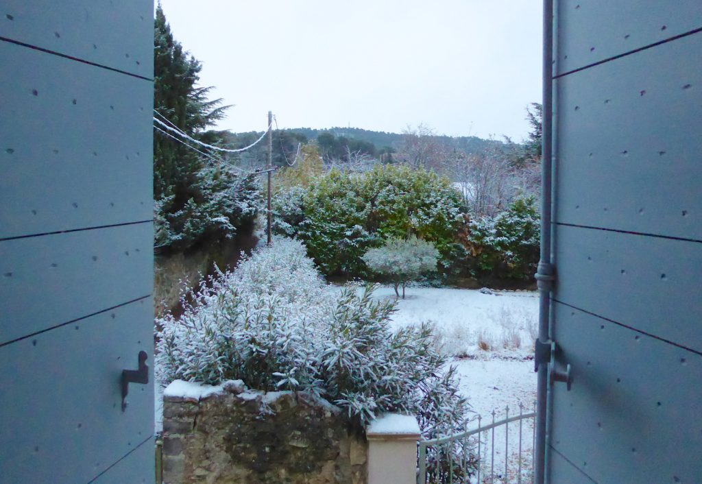 Opeing the xhutters after snowfall in Lourmarin, Luberon, Provence, France